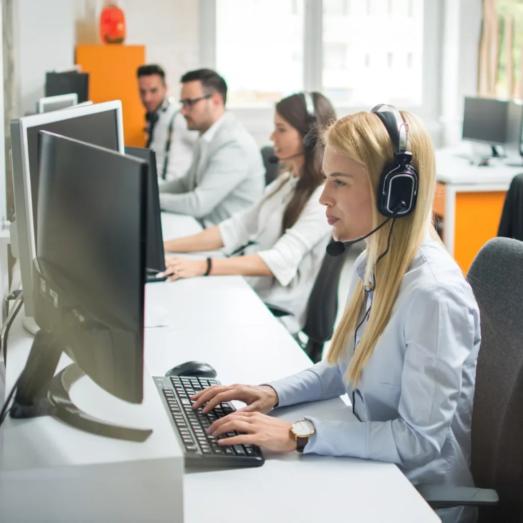 Mehrere junge Mitarbeiter mit Headsets arbeiten konzentriert an ihren Computern in einem modernen Büro, typisches Callcenter- oder Support-Team-Umfeld