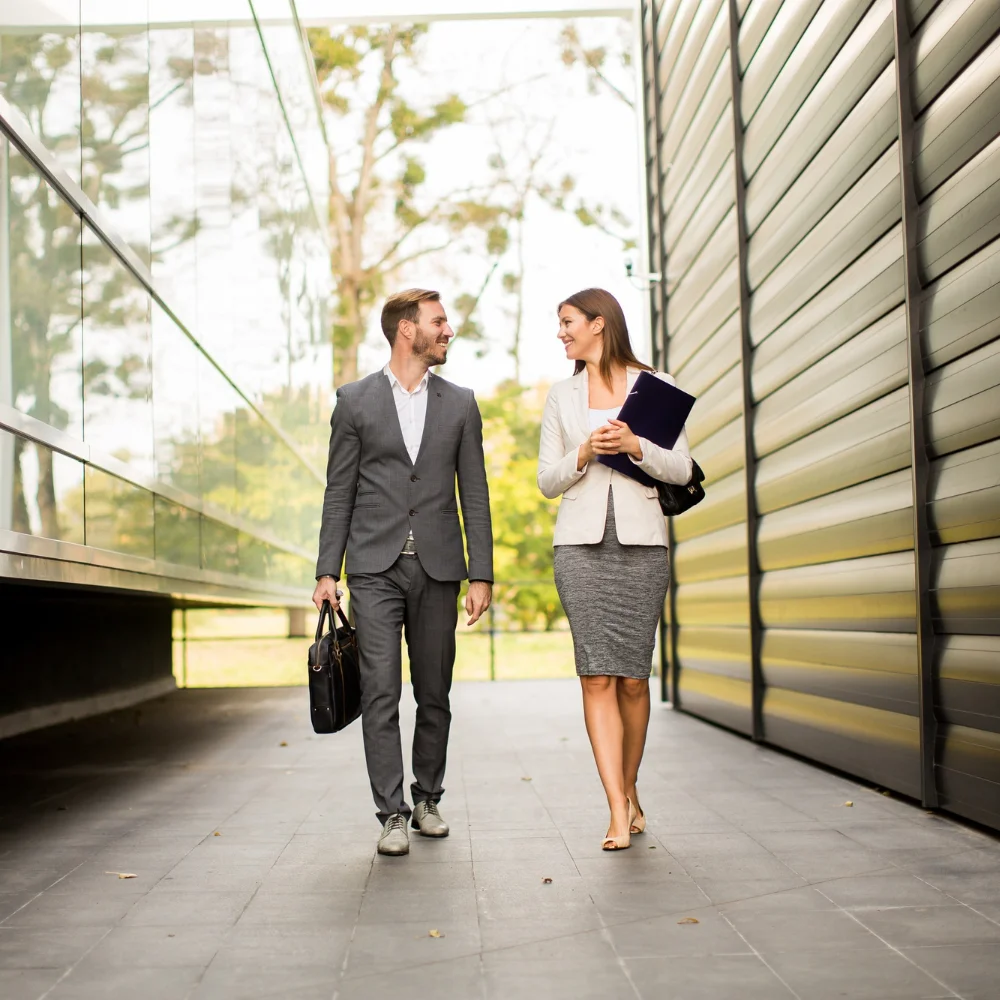 Zwei Geschäftsleute unterhalten sich auf dem Weg durch einen modernen Businesspark