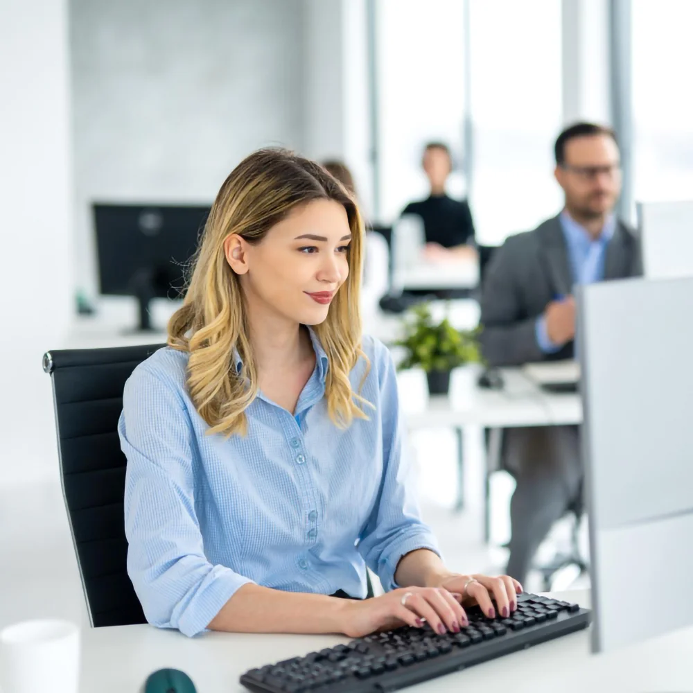 Junge Frau arbeitet konzentriert an einem Computer in einem modernen Büro – symbolisiert SAP-Entwicklung und professionelle IT-Services